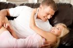 Couple Cuddling On Sofa Stock Photo