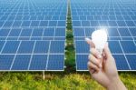 Solar Energy Panels And Light Bulb In Hand Stock Photo