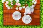 Top View Of The Teapot, Empty  Teacup And Artificial Flowers On A Wooden And Green Stock Photo