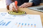 Business Man Hand Holding A Target With Darts Hitting The Center Stock Photo