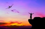 Silhouette Of A Man On The Rock And Silhouette Commercial Plane Stock Photo