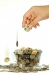 Dropping Coins Into Glass Bowl Stock Photo