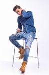 Male Model In Denim Jeans Sitting On A Chair . Studio Shoot Stock Photo