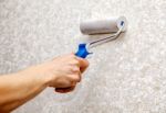 Man's Hand Smoothing The Wallpaper With A Roller Closeup Stock Photo