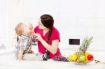 Mother Feeding Child In Kitchen Stock Photo