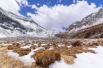 Meadow Brown On The Snow Mountain With Clouds And Blue Sky Stock Photo