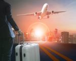 Business Man And Traveling Luggage Standing Against Skyline And Passenger Plane Taking Over Airport Runway Stock Photo