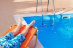 Caucasian Teenage Boy Lying On Stretcher Near Swimming Pool Stock Photo