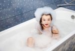 Surprised Little Girl Sitting In A Bath With Soap Suds Stock Photo