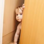 Curious Cute Baby Boy Looking Through Ajar Door Stock Photo