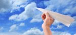 Hand Throwing Paper Plane To Blue Sky Stock Photo