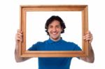 Smiling Guy Looking Through Picture Frame Stock Photo