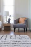 Orange Pillow On Modern Grey Chair With Bedside Table And White Stock Photo