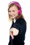 Pretty Musical Girl Enjoying Music And Pointing At You Stock Photo