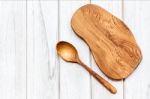 Top View Of Wooden Cutting Board With Spoon On White Wooden Table Stock Photo