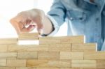 Hand Of Engineer Playing A Blocks Wood Tower Game (jenga) On Blu Stock Photo