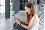 Portrait Of Thai Adult Beautiful Girl Using Her Tablet And Smile In University Stock Photo