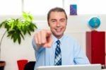 Businessman At Work Desk Pointing At You Stock Photo