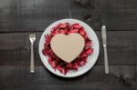 Gift, Plate And Cutlery Surrounded By Dry Petals On Wooden Stock Photo