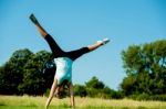 Woman Doing Cartwheel In A Field Stock Photo