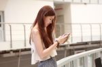 Portrait Of Thai Adult Beautiful Girl Using Her Smart Phone And Smile Stock Photo