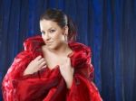 Young Woman In Red Silk On Blue Background Stock Photo