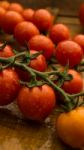 Cherry Tomatoes On Display On Wooden Chopping Board And Wooden Table Stock Photo