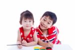 Children Looking At The Camera And Smiling, Holding A Paintbrush Stock Photo