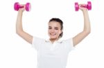 Smiling Girl Working Out. Dumbbells Above Her Head Stock Photo