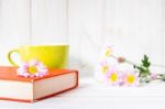 Coffee Cup And Books Or Journal With Flowers Arranged On A Neutral White Painted Desk Stock Photo