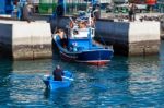 Rowing Fishing Boat To Side Of Harbour Stock Photo