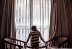 Boy Sitting On A Table Looking Down Down Stock Photo