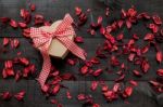 Wrapped Gift  With A Red Bow Surrounded By Dried Petals Stock Photo