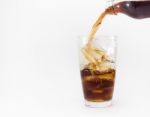 Cola Pouring From A Plastic Bottle Into A Glass Filled With Ice Cubes Stock Photo