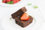 Chocolate Brownie Cake On White Plate Decorated With Strawberrie Stock Photo