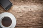 Working Space. Focused On A Cup Of Coffee And Smartphone On Old Wooden Background. Working In The Morning Concept Stock Photo