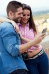 Young Couple Of Tourist In Town Using Mobile Phone Stock Photo