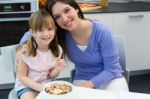 Child Eating Cereals With Her Mom In The Kitchen Stock Photo