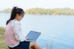 Young Girl With Laptop Sitting On The Riverbank Stock Photo