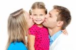 Mom And Dad Kissing Their Beautiful Kid Stock Photo