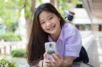 Portrait Of Thai High School Student Uniform Teen Beautiful Girl Using Her Phone And Smile Stock Photo