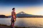 Asian Woman Wearing Japanese Traditional Kimono At Fuji Mountain. Sunset At Kawaguchiko Lake In Japan Stock Photo