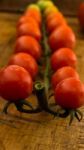 Cherry Tomatoes On Display On Wooden Chopping Board And Wooden Table Stock Photo