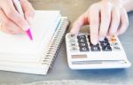 Hand Holding Pen And Pressing Calculator Buttons Stock Photo