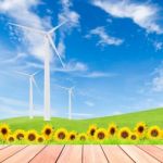 Sunflowers With Wind Turbine On Green Grass Field Against Blue S Stock Photo