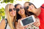 Three Friends Taking Photos With A Smartphone Stock Photo