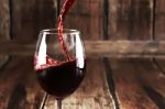 Red Wine Is Poured From Bottle To Glass Stock Photo