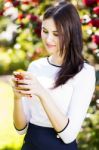 Beautiful Girl Typing Text Message On Her Smart Phone In The Gar Stock Photo