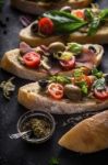 Slices Of Ciabatta With Olives , Tomatoes And Basil On The Black Stone Table Vertical Stock Photo