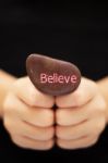 Hand Holding Believe Stone Stock Photo